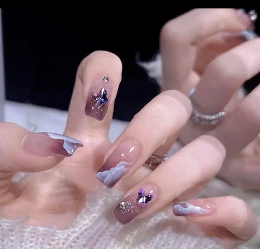 Shorter Length Coffin Press on Nails. Mauve with White Clouds, Purple Butterflies & Jewels. Easy and quick to apply. Great for those special occasions, parties or add an edge to any outfit. Gorgeous, flattering and you can re-use them again and again.